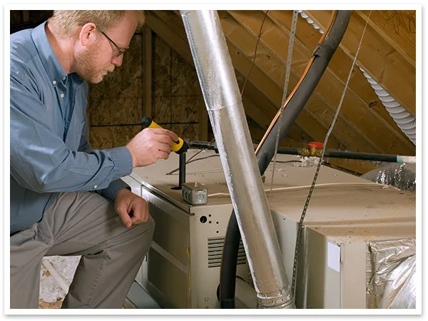 Technician completing a heating maintenance & inspection check in an attic