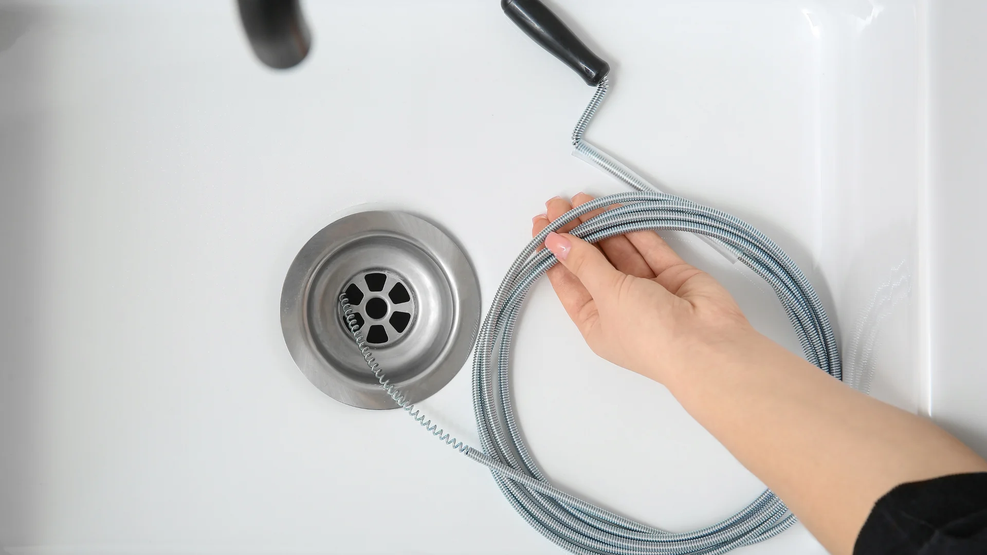 Technician using a drain snake or auger to clean a drain